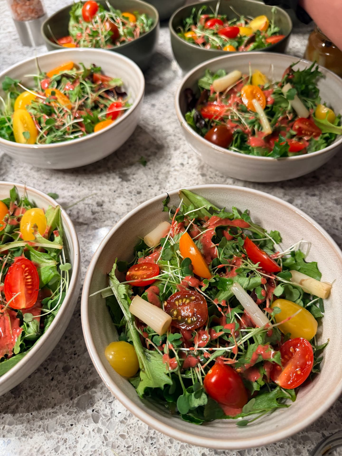 Bowls of mixed greens and microgreens with heirloom cherry tomatoes and a berry vinaigrette